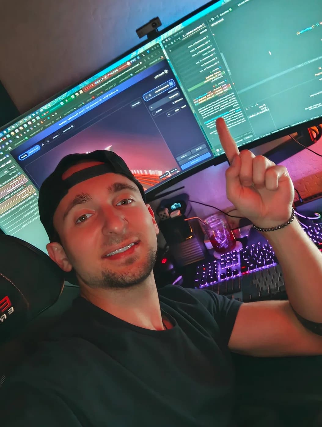 Alec at his desk, pointing up at the code on his monitor